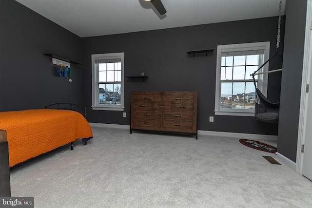 bedroom featuring ceiling fan, light colored carpet, and multiple windows