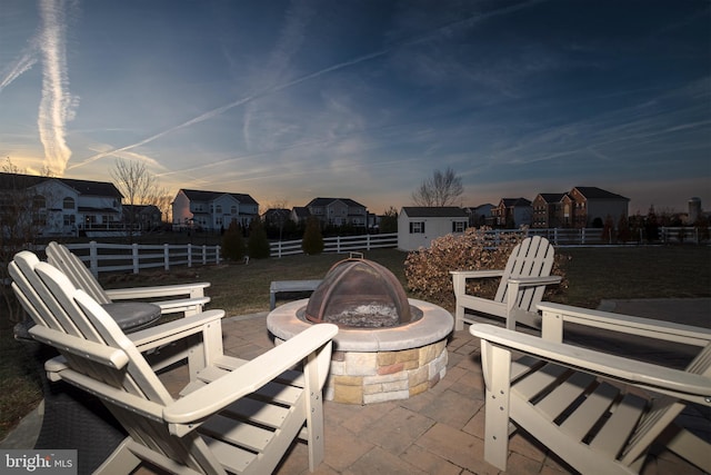 patio terrace at dusk featuring an outdoor fire pit and a storage unit