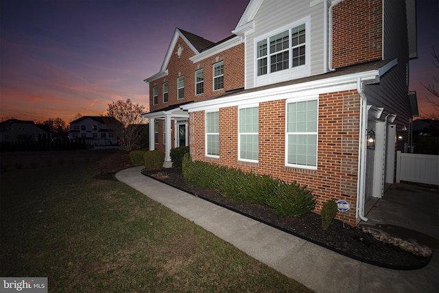 property exterior at dusk featuring a lawn