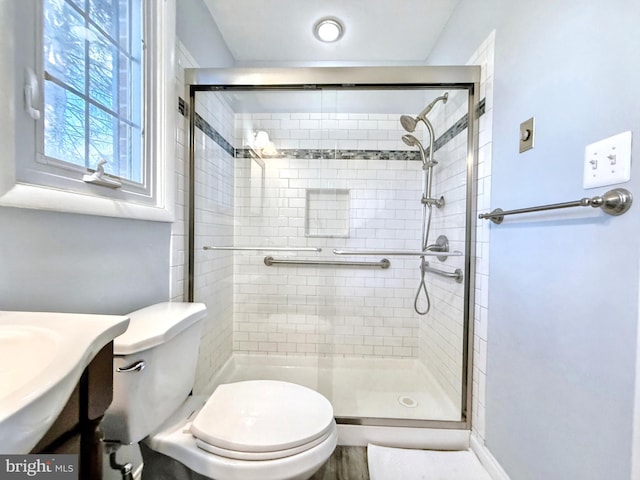 bathroom featuring a shower with door, vanity, and toilet