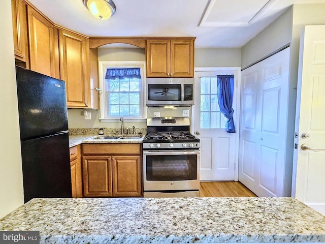 kitchen featuring sink, light hardwood / wood-style flooring, stainless steel appliances, and light stone countertops