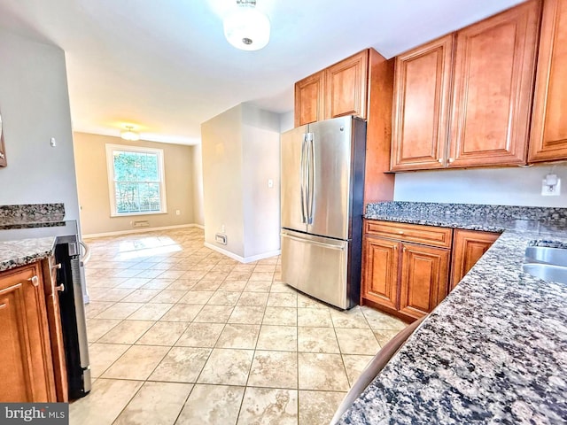 kitchen with dark stone countertops, range with electric cooktop, stainless steel refrigerator, and light tile patterned flooring