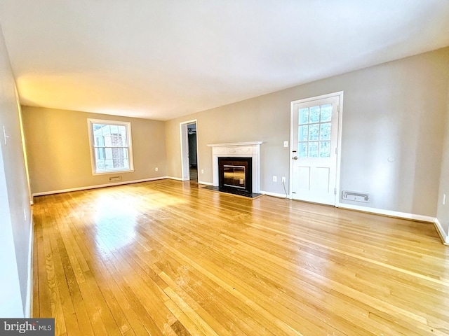 unfurnished living room featuring a fireplace and light hardwood / wood-style floors