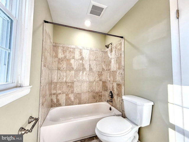 bathroom featuring tiled shower / bath combo and toilet