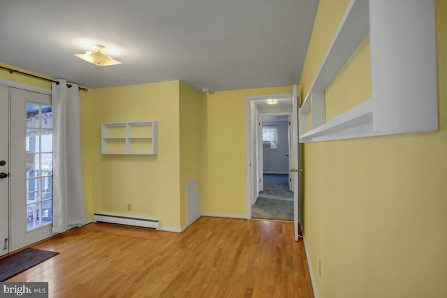 interior space with a baseboard heating unit, light hardwood / wood-style flooring, and french doors