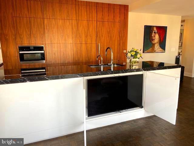 kitchen featuring dark parquet flooring, sink, kitchen peninsula, wall oven, and oven