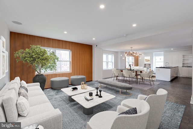 living room with plenty of natural light, wooden walls, dark hardwood / wood-style flooring, and a notable chandelier