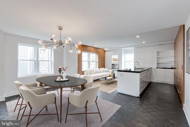 dining area featuring dark parquet flooring, sink, and a notable chandelier