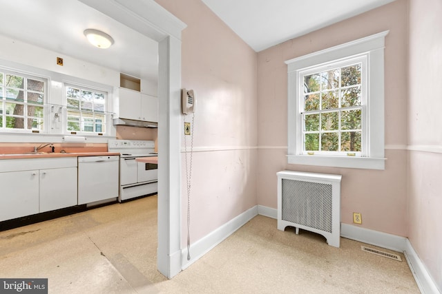 kitchen with white cabinetry, white appliances, radiator, and sink