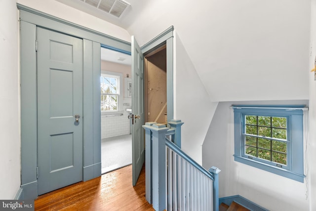 foyer entrance featuring lofted ceiling, hardwood / wood-style flooring, and brick wall