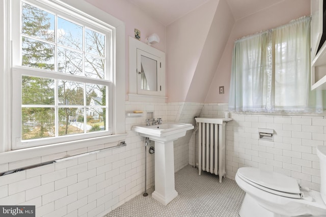 bathroom featuring tile patterned flooring, radiator, tile walls, and toilet