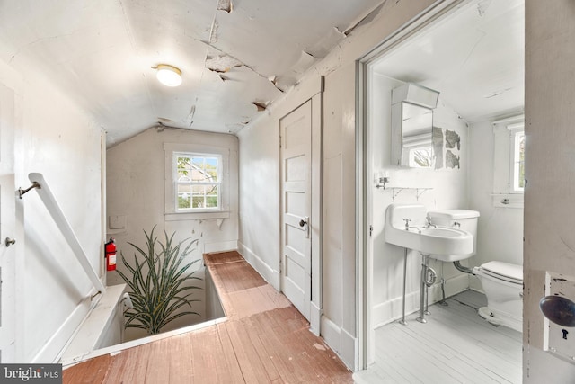 bathroom featuring hardwood / wood-style flooring, vaulted ceiling, and toilet