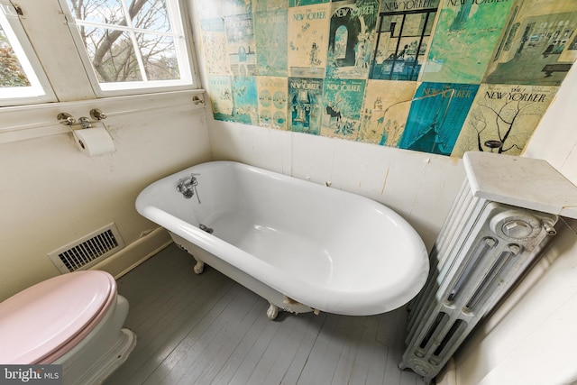 bathroom featuring a tub, hardwood / wood-style floors, and toilet