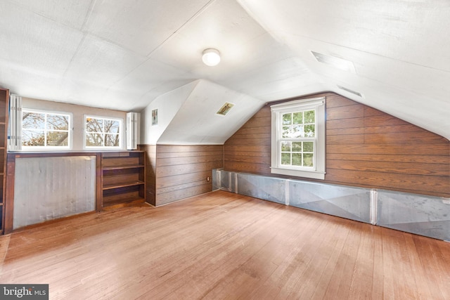 bonus room featuring wood walls, lofted ceiling, and light wood-type flooring