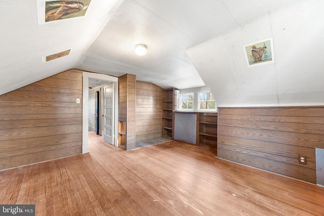 bonus room featuring hardwood / wood-style flooring, lofted ceiling, and wood walls