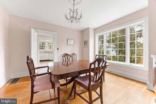 dining room with a wealth of natural light, a notable chandelier, and light hardwood / wood-style floors