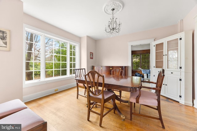 dining space with an inviting chandelier and light hardwood / wood-style flooring