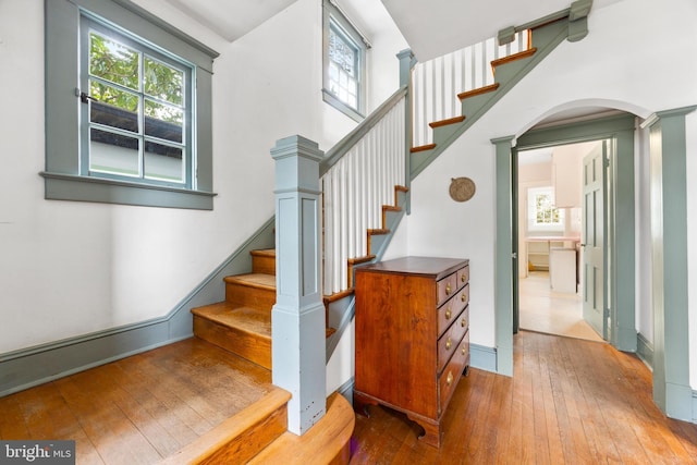 stairway with a towering ceiling and hardwood / wood-style floors