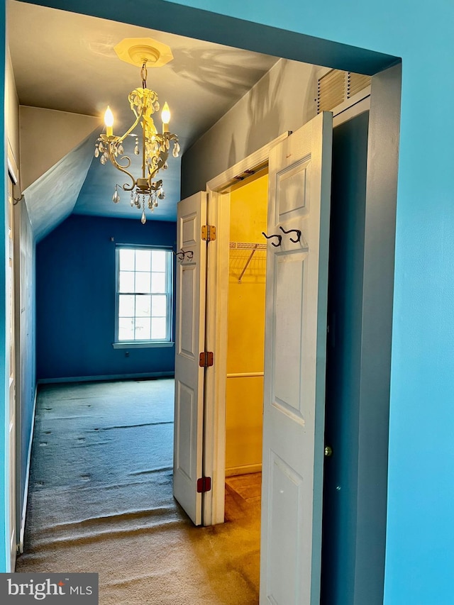 hallway with lofted ceiling, carpet floors, and a notable chandelier