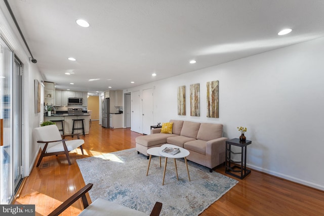 living area with recessed lighting, baseboards, and wood finished floors