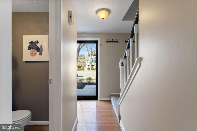 foyer entrance featuring a textured ceiling, stairs, baseboards, and hardwood / wood-style flooring