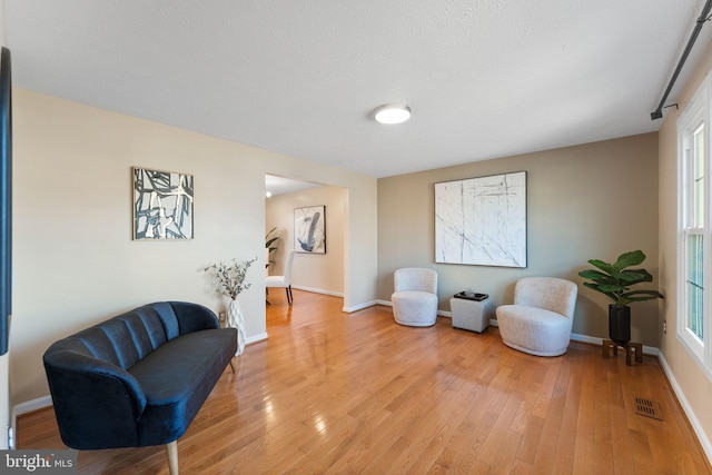 living area featuring visible vents, light wood-type flooring, and baseboards