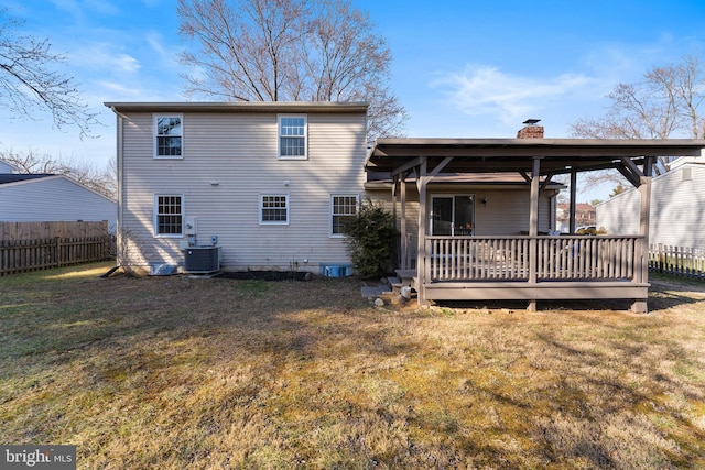 rear view of property featuring fence, a yard, cooling unit, a wooden deck, and a chimney