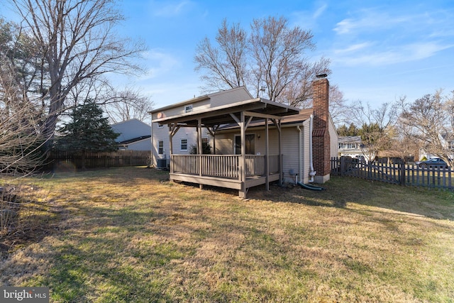 rear view of property with a chimney, a lawn, a wooden deck, and a fenced backyard