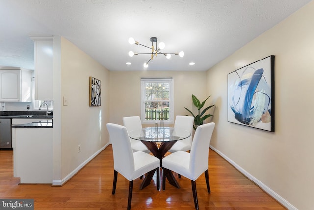 dining room with a textured ceiling, baseboards, light wood-type flooring, and a chandelier