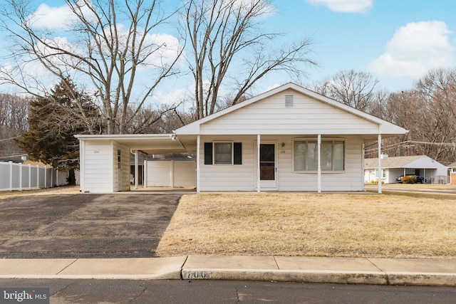 ranch-style house featuring a front yard, a carport, and covered porch