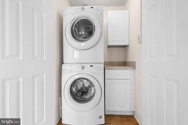 laundry room with cabinets and stacked washing maching and dryer