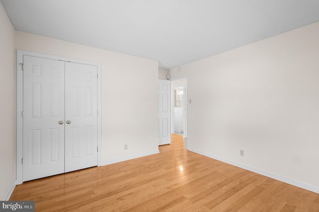 unfurnished bedroom with a closet and light wood-type flooring