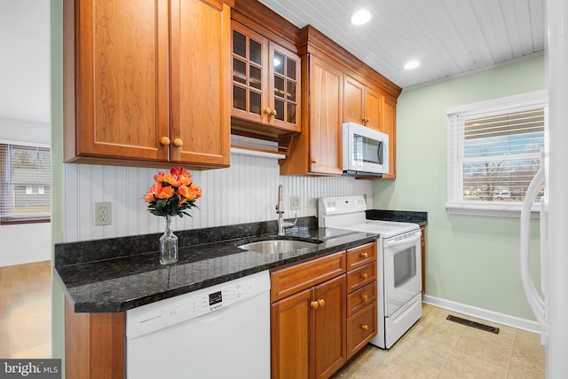 kitchen featuring white appliances, sink, and dark stone countertops