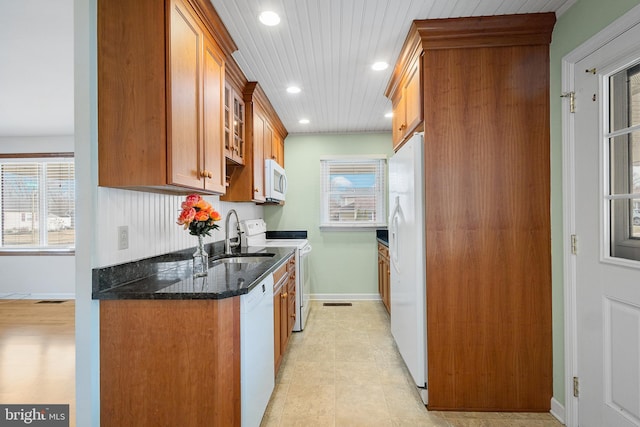 kitchen with sink, white appliances, dark stone counters, and light tile patterned flooring