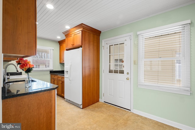 kitchen featuring white fridge with ice dispenser, sink, wooden ceiling, and dark stone counters