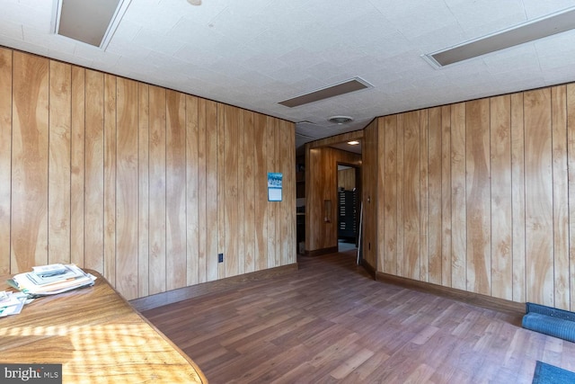 unfurnished room with hardwood / wood-style floors and wood walls