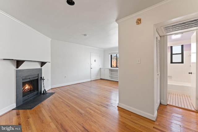 unfurnished living room with ornamental molding and light hardwood / wood-style floors