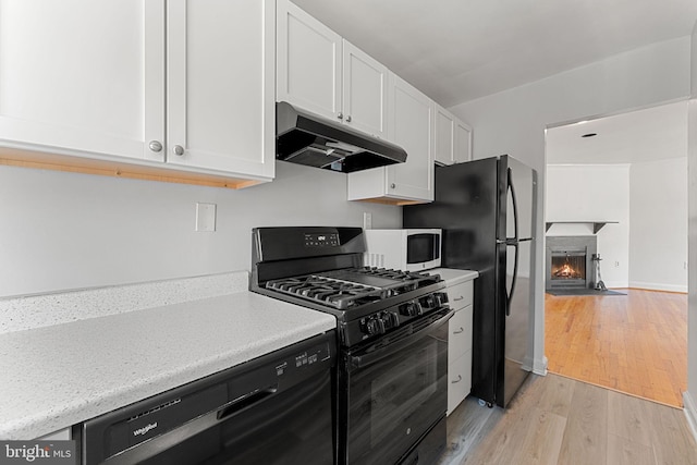 kitchen featuring white cabinets, light wood-type flooring, and black appliances