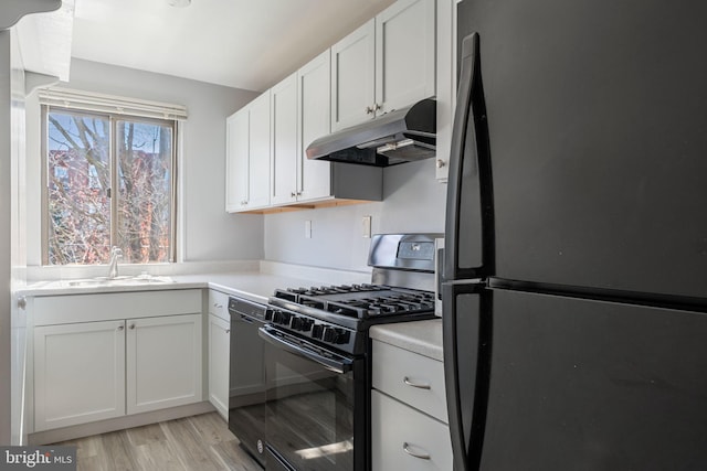 kitchen featuring sink, light hardwood / wood-style flooring, black appliances, and white cabinets