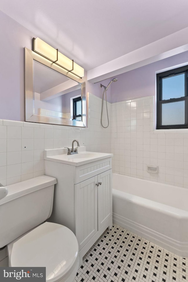 full bathroom with tiled shower / bath, tile walls, tile patterned flooring, vanity, and toilet