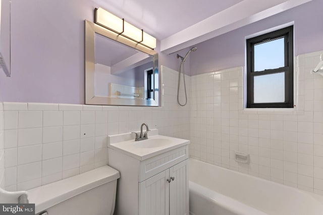 full bathroom featuring tiled shower / bath combo, vanity, tile walls, and toilet