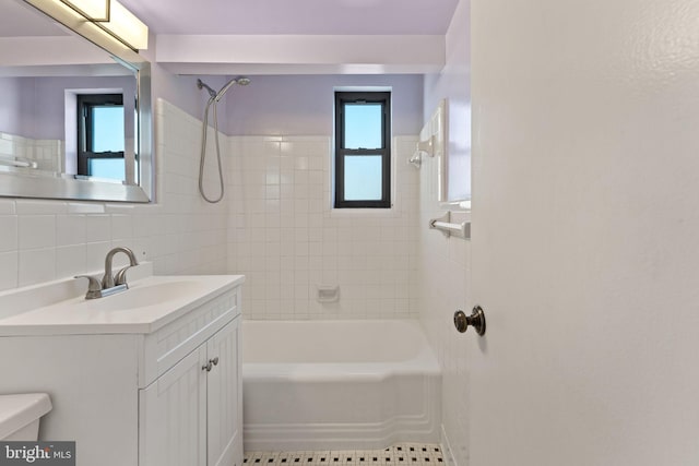 full bathroom with toilet, tiled shower / bath, tile walls, vanity, and tile patterned flooring