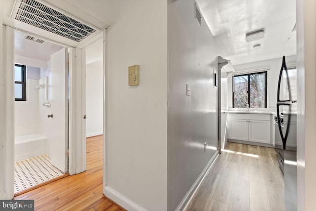 corridor featuring sink and light hardwood / wood-style flooring