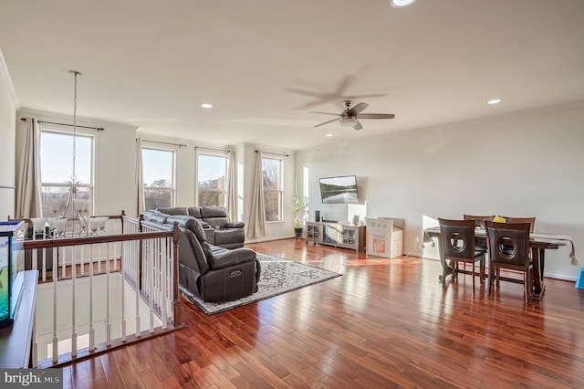 living room with ornamental molding, ceiling fan with notable chandelier, and hardwood / wood-style floors