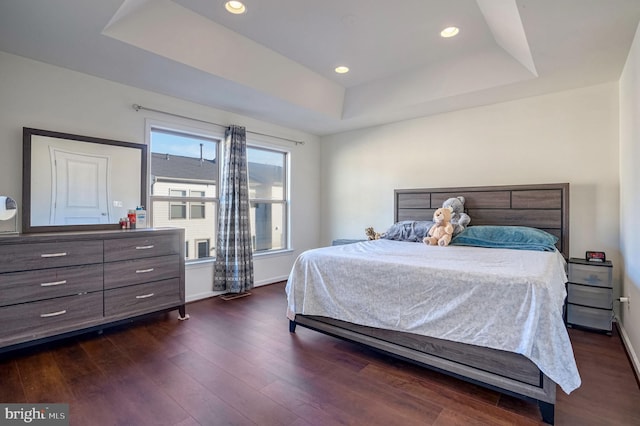 bedroom featuring a raised ceiling and dark hardwood / wood-style flooring