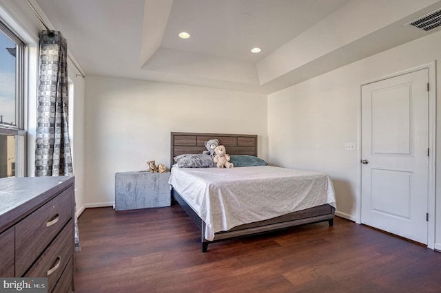 bedroom with dark hardwood / wood-style flooring and a raised ceiling