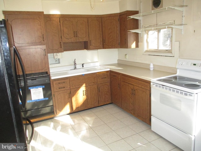 kitchen featuring sink, white range with electric cooktop, black refrigerator, wall oven, and light tile patterned flooring