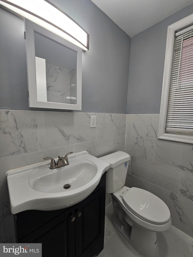 bathroom featuring vanity, tile walls, and toilet