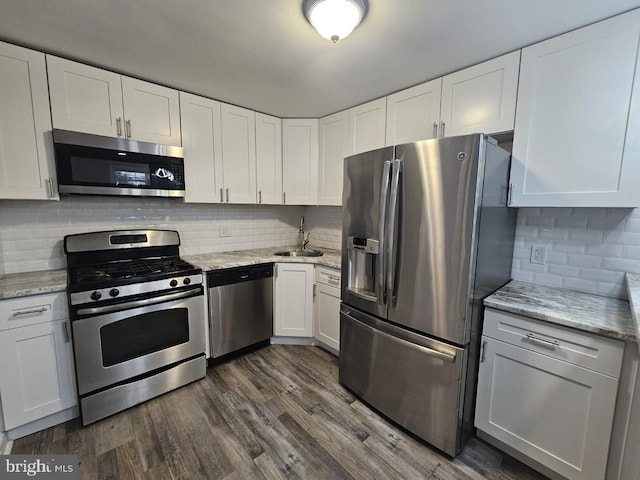 kitchen featuring sink, appliances with stainless steel finishes, dark hardwood / wood-style flooring, light stone countertops, and white cabinets