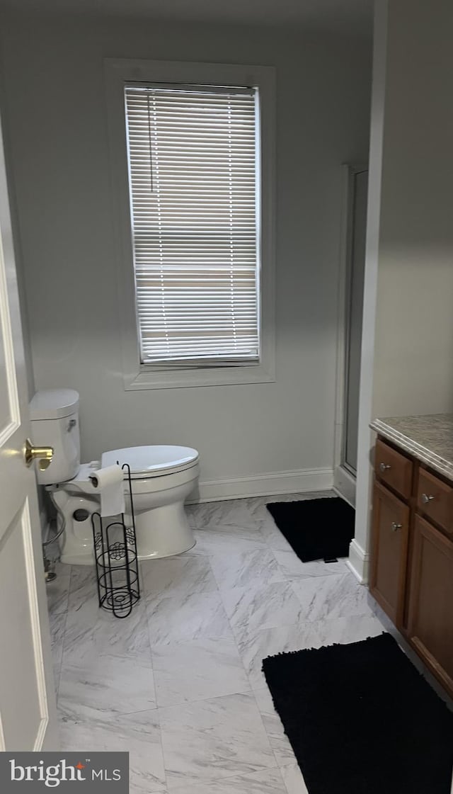 bathroom with walk in shower, vanity, and toilet